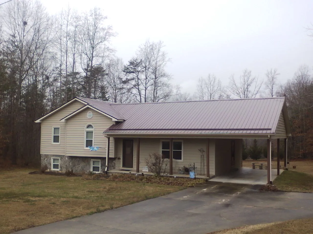 Burgundy metal roof on a tan split level home with an attached carport in Eagle